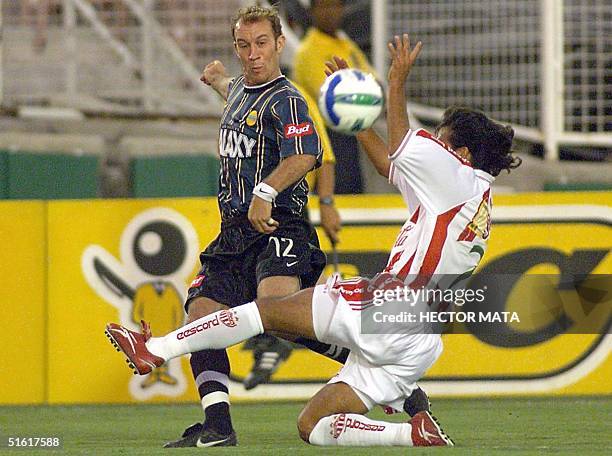 Simon Elliot of the Los Angeles Galaxy passes the ball over Necaxa player Salvador Cabrera of Mexico during their match at the Rose Bowl 18 August...