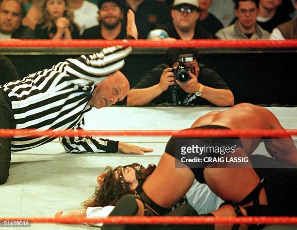 Minnesota Governor, former professional wrestler and guest referee Jesse Ventura administers the three count as wrestler Stone Cold tries...