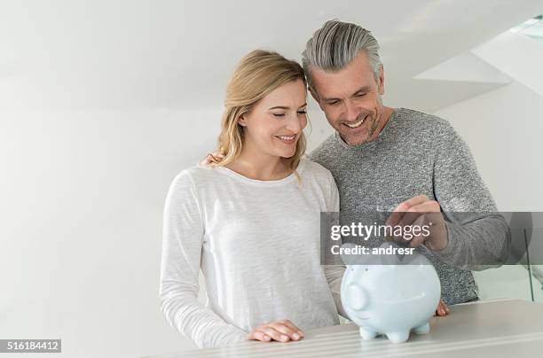 couple saving money in a piggybank - couple saving piggy bank stock pictures, royalty-free photos & images