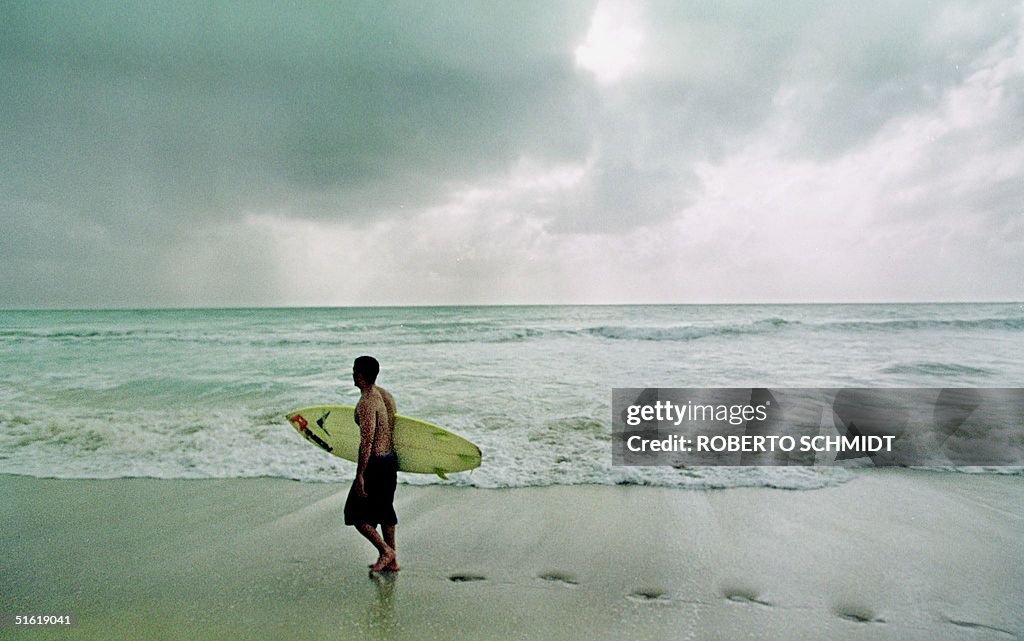 A surfer walks along the beach in South Miami Beac