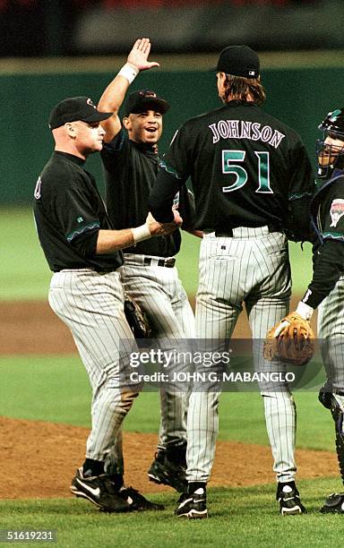 Arizona Diamondbacks shortstop Tony Womack gives a high five to ace pitcher Randy ''The Big Unite" Johnson as teammates Matt Williams and catcher...