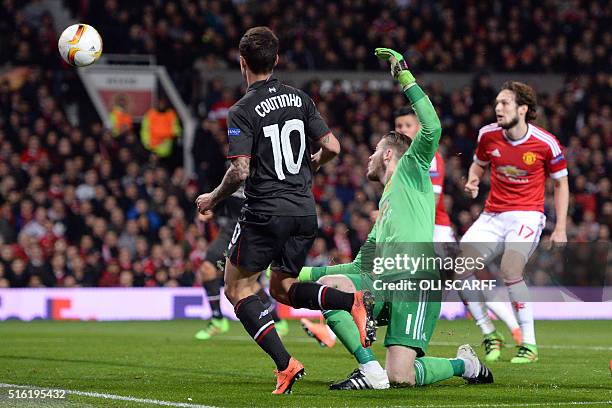 Liverpool's Brazilian midfielder Philippe Coutinho shoots past Manchester United's Spanish goalkeeper David de Gea to score their first goal during...