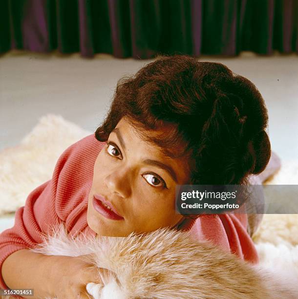 American singer and actress Eartha Kitt posed on a fur rug in 1965.