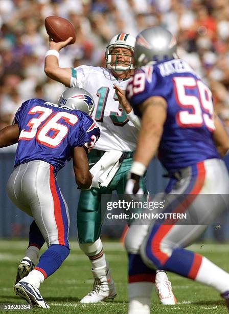 Miami Dolphins starting quarterback Dan Marino gets pressured by Lawyer Milloy of the New England Patriots as he throws an interception to Andy...