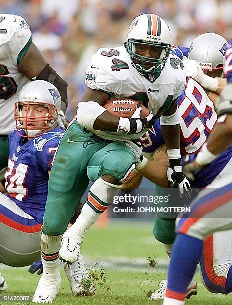 Running back Cecil Collins of the Miami Dolphins runs between Chris Sullivan and Andy Katzenmoyer of the New England Patriots during their 17...