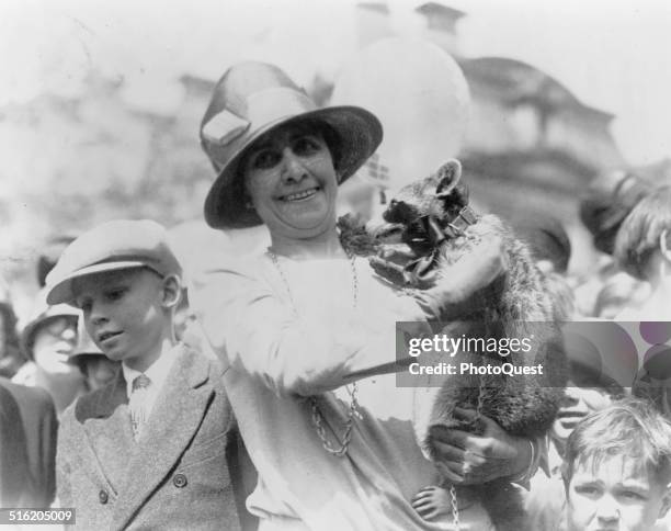 First Lady Grace Coolidge holds up her pet raccoon, Rebecca, for a crowd of children at the annual White House Easter Egg Roll, Washington DC, April...