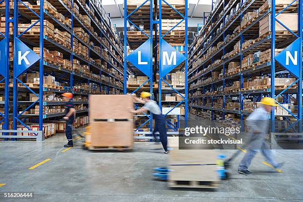coworkers carrying cardboard box in warehouse. - scheepvaart stockfoto's en -beelden