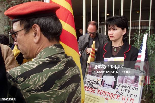 Thu Ngh Dang holds up a placard with a picture of a U.S. Veteran killed in Vietnam that says "Please Remember Him" during a protest outside the ACLU...