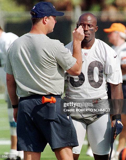 Denver Broncos running back Terrell Davis gets help from equipment manager Doug West to put on some greasepaint under his eyes moments before the...