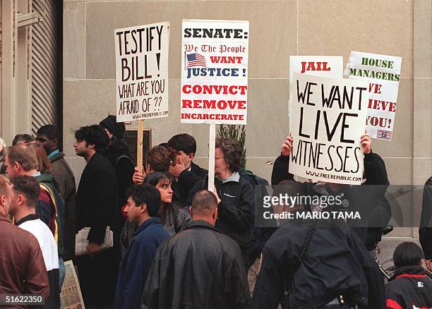 Protesters demanding live witness testimony at US President Bill Clinton's impeachment trial and his removal from office wave posters in front of the...