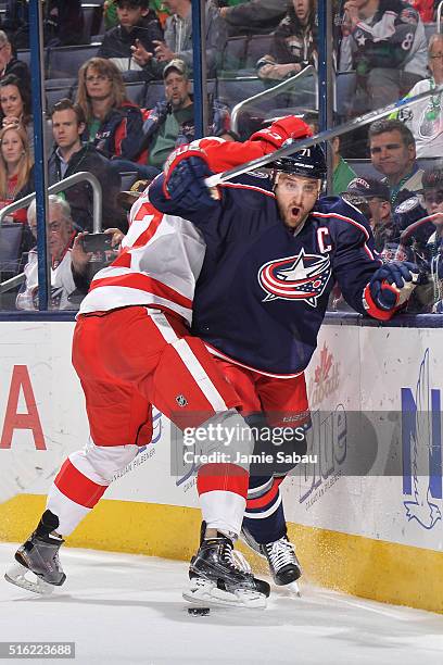 Nick Foligno of the Columbus Blue Jackets attempts to break free of the check from Alexey Marchenko of the Detroit Red Wings while chasing after a...