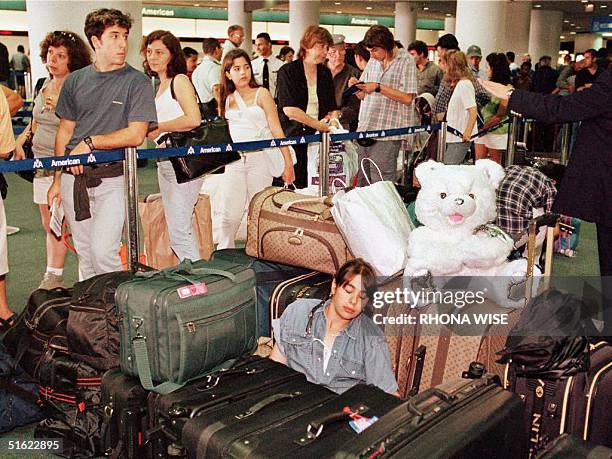 An unidentified teenage passenger sleeps on her luggage as she waits with other passengers in the international check-in line 12 February at Miami...