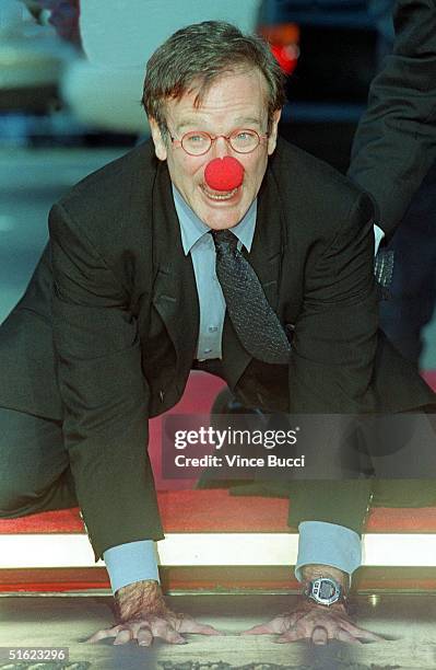 Academy Award-winning actor Robin Williams wears a clown nose as he places his hands in cement during his hand and footprint ceremony outside Mann's...