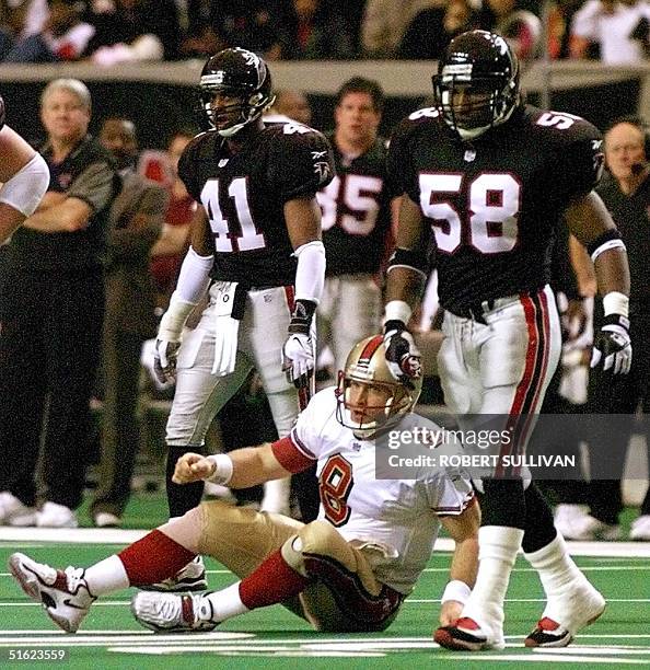 After throwing an incomplete pass, quarterback Steve Young of the San Francisco 49ers sits on the ground between Atlanta Falcons defenders Chris...