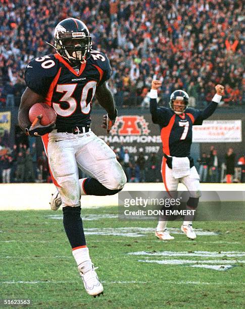 Denver Broncos quarterback John Elway signals a touchdown as running back Terrell Davis runs for his second touchdown of the day against the Miami...