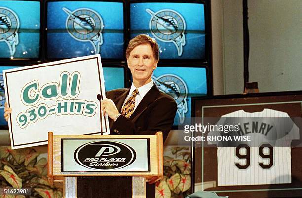 New Florida Marlins owner John W. Henry holds up a phone number to purchase season tickets to his newly acquired team at a press conference 20...