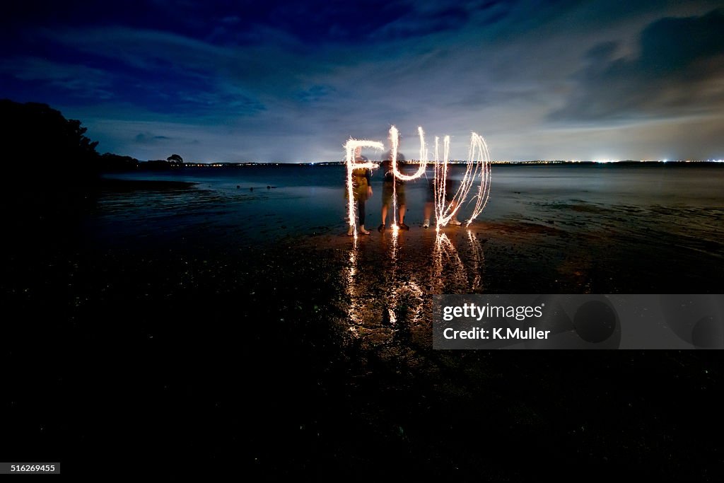 'FUN' written with sparklers on dark beach