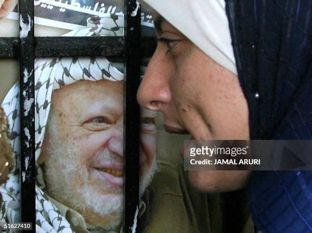 Palestinian girl walks past a poster of Palestinian leader Yasser Arafat at the West Bank university of Bir Zeit, in this town 30 October 2004....