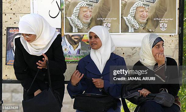 Palestinian girls sit in front of posters of Palestinian leader Yasser Arafat at the West Bank university of Bir Zeit, in this town 30 October 2004....