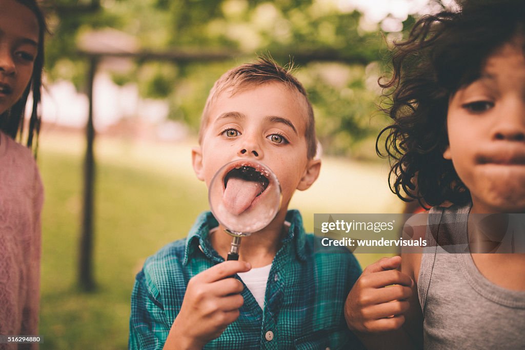 Junge mit einer Lupe, die seine Zunge Suchen groß