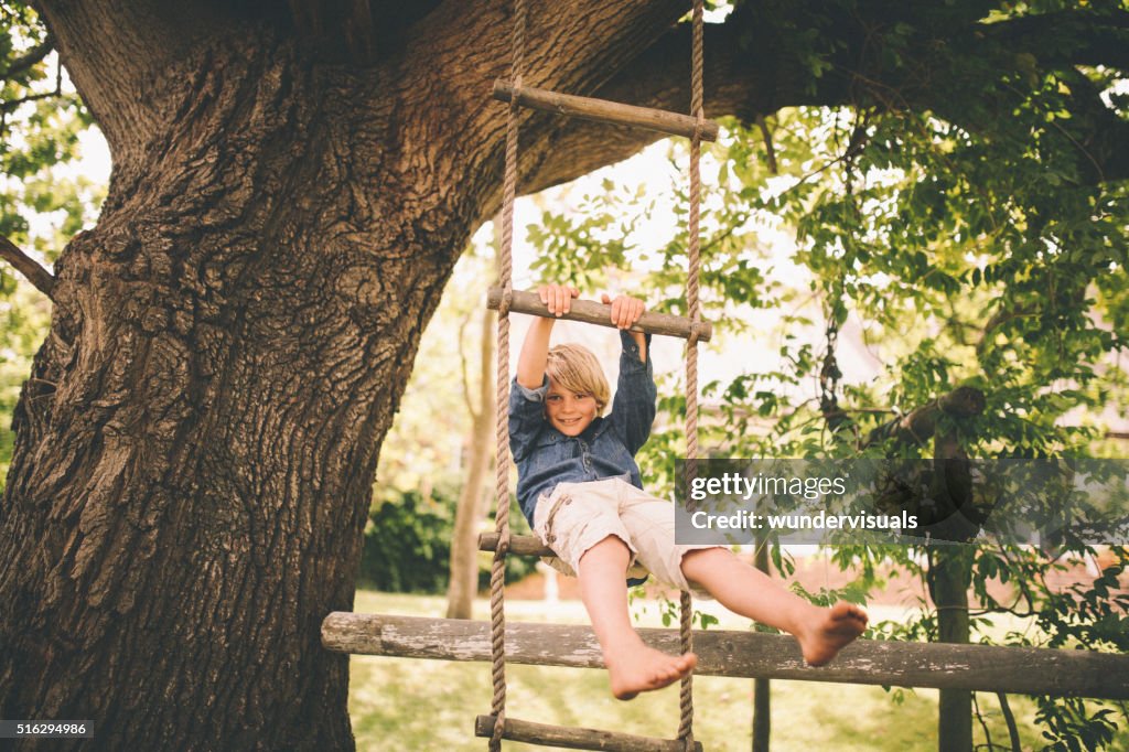 Junge schwingen in einer Strickleiter von Baum im Park