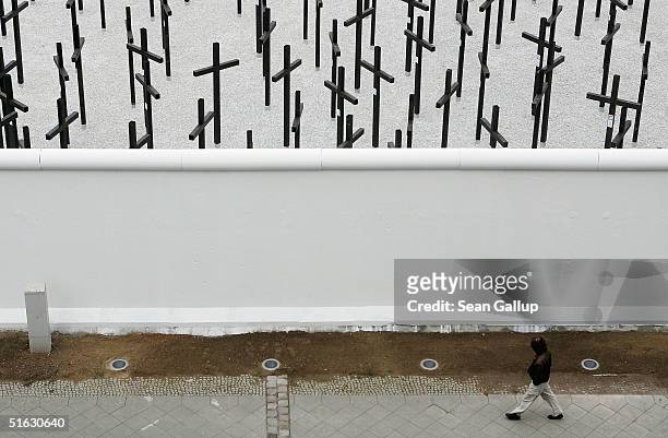 Man walks past a rebuilt section of the Berlin Wall and crosses that commemorate its victims on the day of the memorial's unveiling, on October 31,...