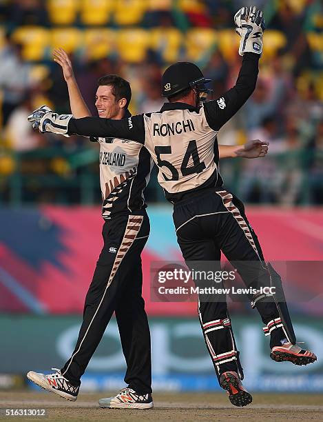 Mitchell Santner of New Zealand is congratulated by Luke Ronchi of New Zealand on the wicket of David Warner of Australia, after he was caught by...