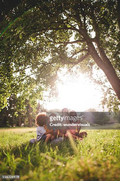 african-american family sitting in beautiful park blowing bubble - family garden play area stock pictures, royalty-free photos & images