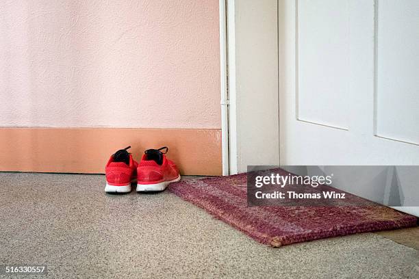 running shoes and door mat - fußmatte stock-fotos und bilder