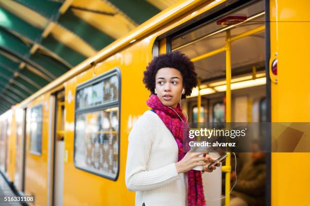 junge afrikanische frau einsteigen in einen zug - öffentliches verkehrsmittel stock-fotos und bilder