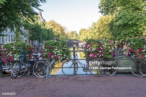 bicycles parkes on a bridge in amsterdam - amsterdam bike stock-fotos und bilder