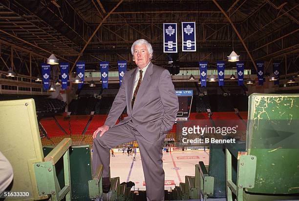 Portrait of Toronto Maple Leafs General Manager and 2004 Hall of Fame inductee Cliff Fletcher as he poses with his leg up in the stands of Maple Leaf...