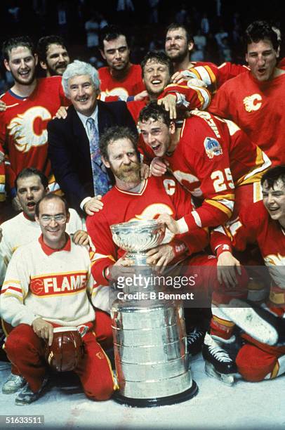 The 1989 Calgary Flames and general manager Cliff Fletcher pose for a team photo around the Stanley Cup which they have just won in a game against...