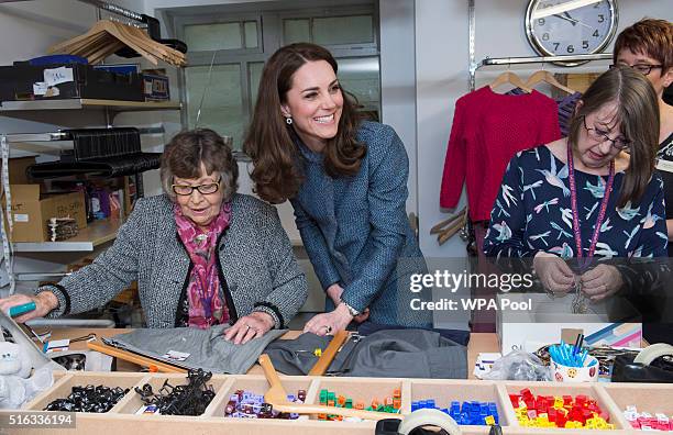 Catherine, Duchess of Cambridge helps to sort clothes as she takes a tour of the new EACH charity shop that she officially opened earlier today on...