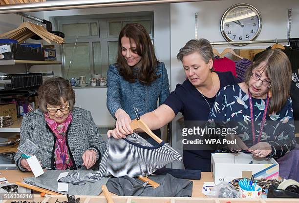 Catherine, Duchess of Cambridge helps to sort clothes as she takes a tour of the new EACH charity shop that she officially opened earlier today on...