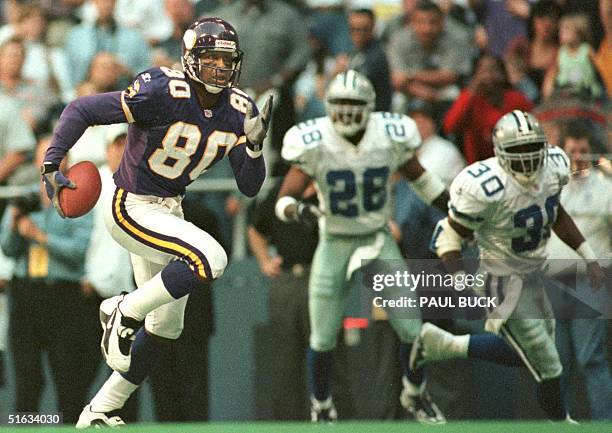 Cris Carter of the Minnesota Vikings runs away from Dallas Cowboys defenders Darren Woodson and Kenny Wheaton en route to a 54 yard touchdown...