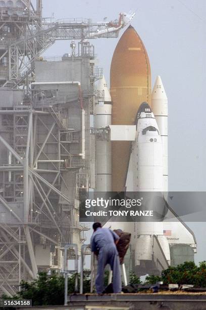The space shuttle Endeavour sits on launch pad 39-A in a light rain 03 December as a NASA employee services remote cameras after her early morning...