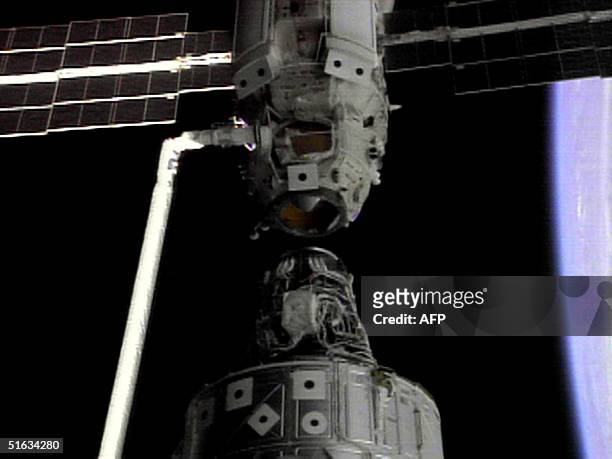 The US space shuttle Endeavor's robot arm holds the Russian Zarya control module a few feet from the US Unity connecting module prior to bringing the...