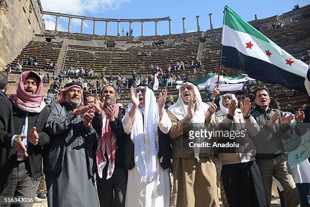 Syrian opponents gathered at the Bosra Ancient City chant slogans and hold Syrian flags during a protest against Assad Regime after Friday prayers in...