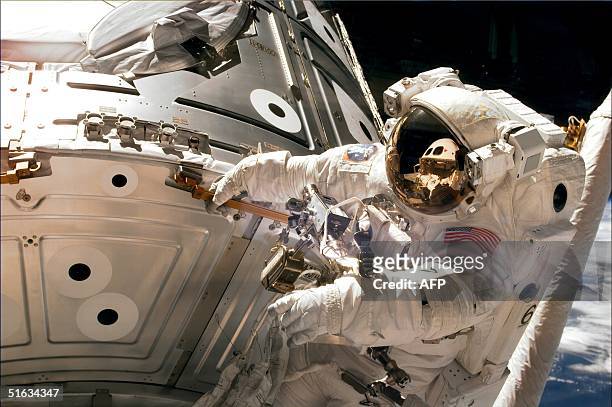 Space shuttle Endeavour crewmember Jim Newman grabs a hold of the US Unity connecting module 07 December as he works removing covers and connecting...