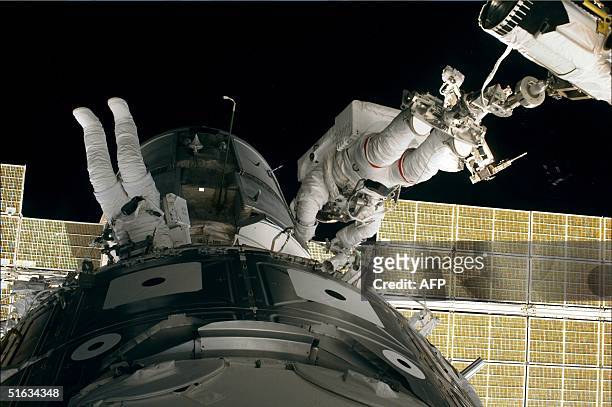 Space shuttle Endeavour crewmembers Jim Newman and Jerry Ross work on a section between the US Unity connecting module and the Russian Zarya control...