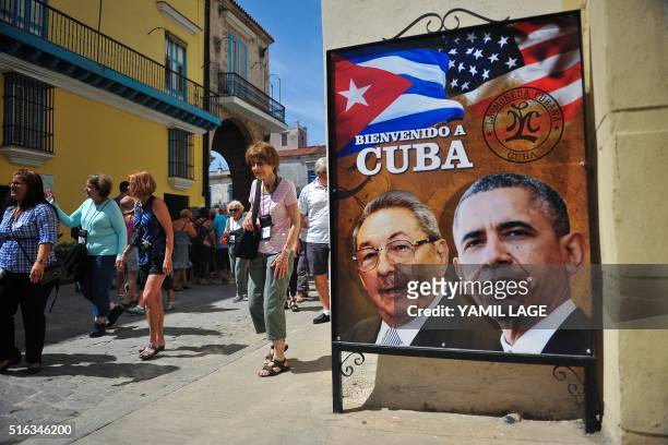 Tourists walk next to a poster of Cuban President Raul Castro and US president Barack Obama in Havana, on March 18, 2016. US president Barack Obama...