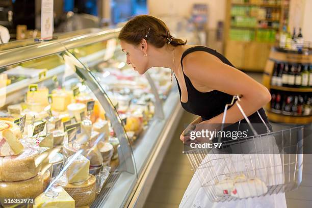 woman buys cheese in the supermarket - delicatessenzaak stockfoto's en -beelden