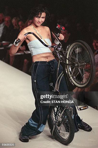 Model rides a bicycle while wearing a pale blue tube top and baggy denim trousers during the Buggirl portion of the Girls Rule! fashion show 02...