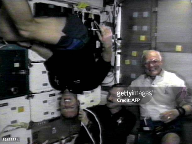 Space shuttle Discovery crewmembers US Pilot Steve Lindsey, US Commander Curt Brown and US Astronaut John Glenn demonstrate the microgravity...