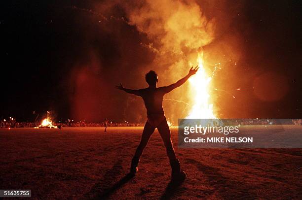 Burning Man" participant holds up his arms as the wooden man effigy is burned at the conclusion of the week-long "Burning Man Festival" 06 September...