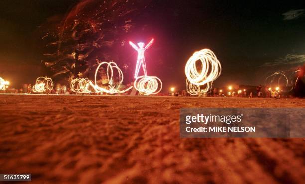 Dancers at the "Burning Man" festival create patterns with fireworks in the Black Rock Desert of Nevada just prior to burning a five-story, neon-lit...