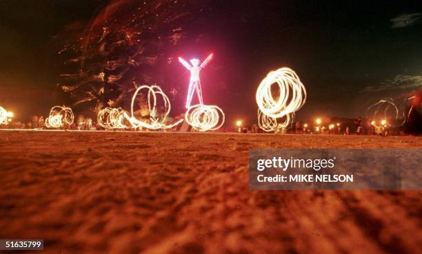 Dancers at the "Burning Man" festival create patterns with fireworks in the Black Rock Desert of Nevada just prior to burning a five-story, neon-lit...