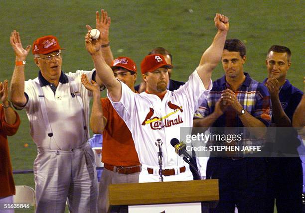 Mark McGwire of the St. Louis Cardinals holds the ball he hit for his 62nd home run of the season against the Chicago Cubs, which was given to him by...