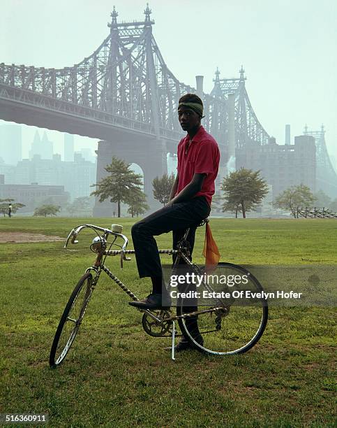 Young man on a bicycle in front of Queensboro Bridge, New York, 1964.